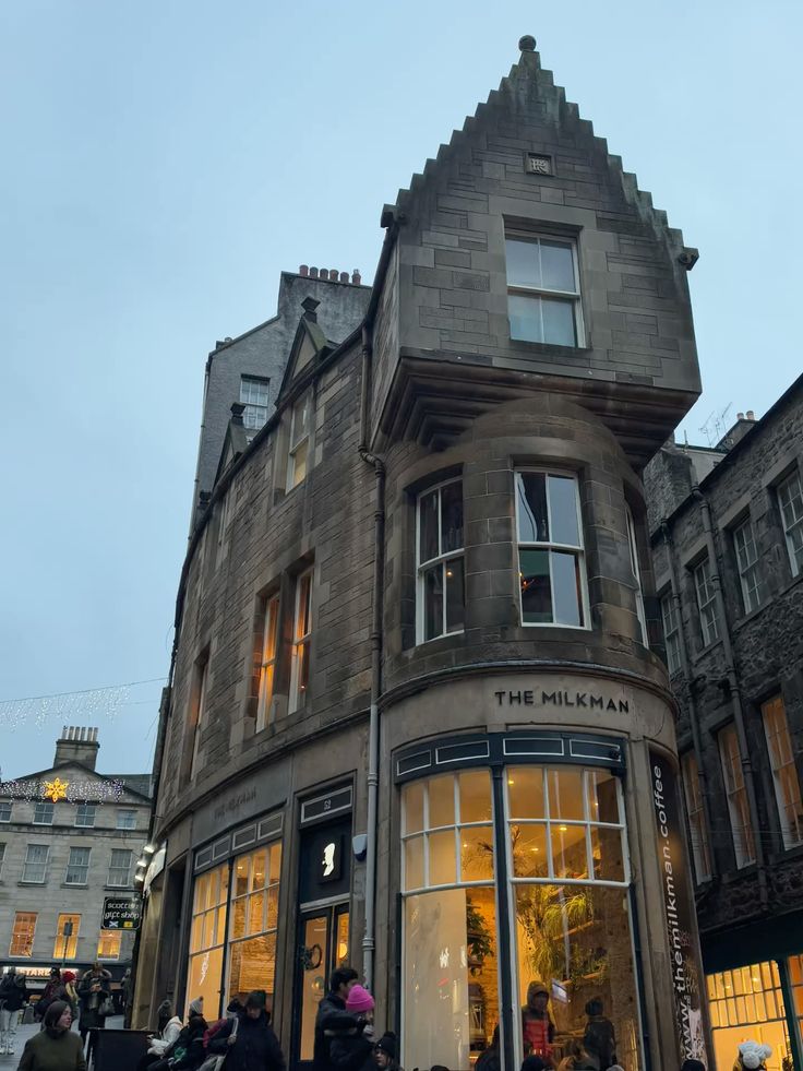 Stone corner building with stepped gable roof housing The Milkman café in Edinburgh at dusk