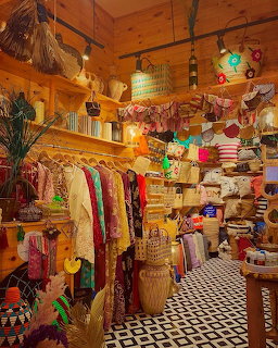 Cozy vintage boutique with wooden walls, colorful clothes, stacked textiles, and checkered floor