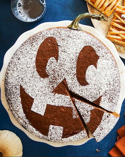Round pumpkin-molasses cake with powdered sugar jack-o'-lantern face and two slices cut