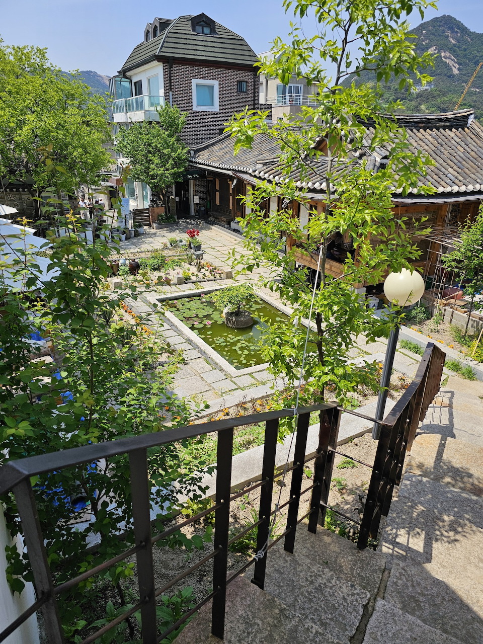 Overhead view of a courtyard garden with stone paths and traditional Korean hanok rooftops in Seoul