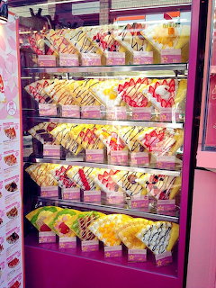 Display case with colorful replica Japanese crepes and desserts topped with fruit and cream