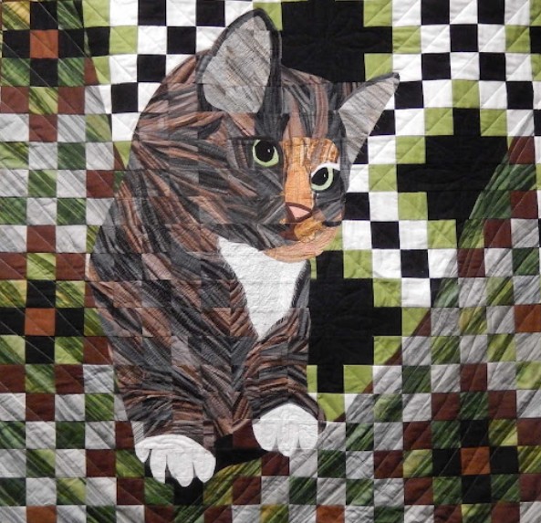 Patchwork quilt featuring a tabby cat with a black, white, and green checker pattern background