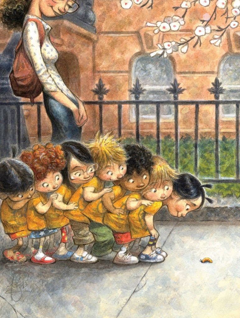 Children in yellow shirts standing in line measuring height against brick wall with adult observing