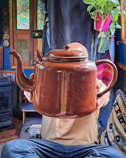 Vintage copper teapot on stand in eclectic interior with blue walls and plants
