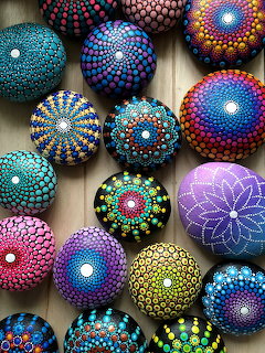 Colorful painted pebbles with dotted mandala patterns arranged on a wooden surface