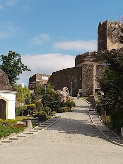 Stone path leading up to Bolków Castle ruins with tower and walls surrounded by greenery