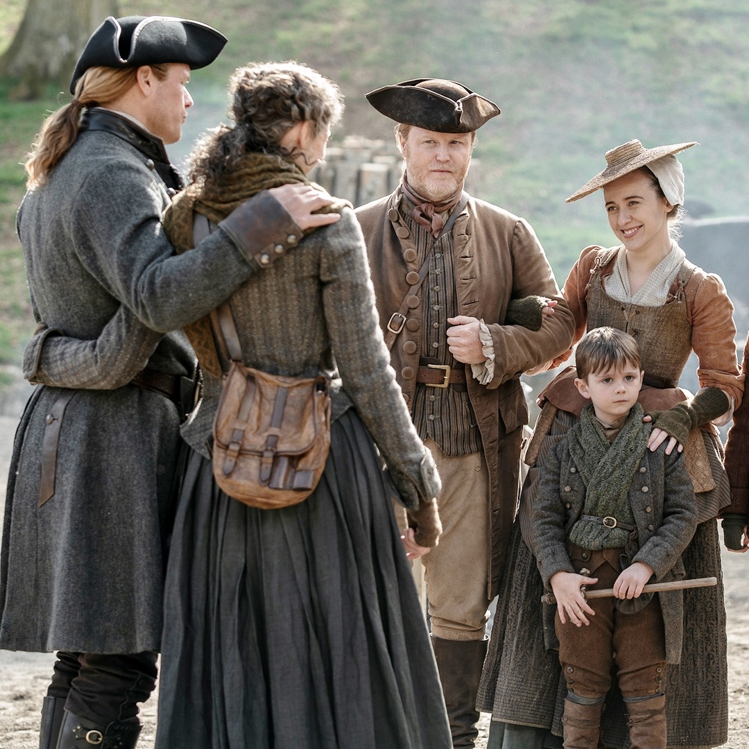 Group of people in 18th-century colonial clothing with tricorn hats standing together outdoors