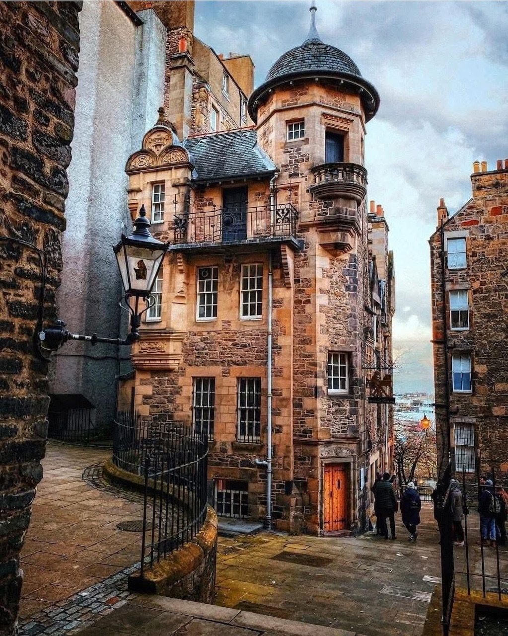 Historic sandstone buildings with turret and street lamp in a narrow Edinburgh Old Town close