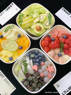 Four white bowls of assorted fresh fruits and mochi desserts arranged on a dark table