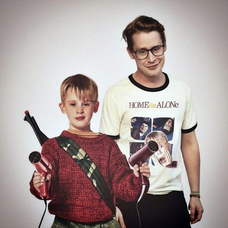 Boy and man posing with hair dryers in a studio, with the man wearing a Home Alone shirt