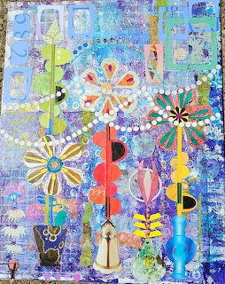 Abstract collage art with colorful flowers, beads, and geometric shapes on blue textured background