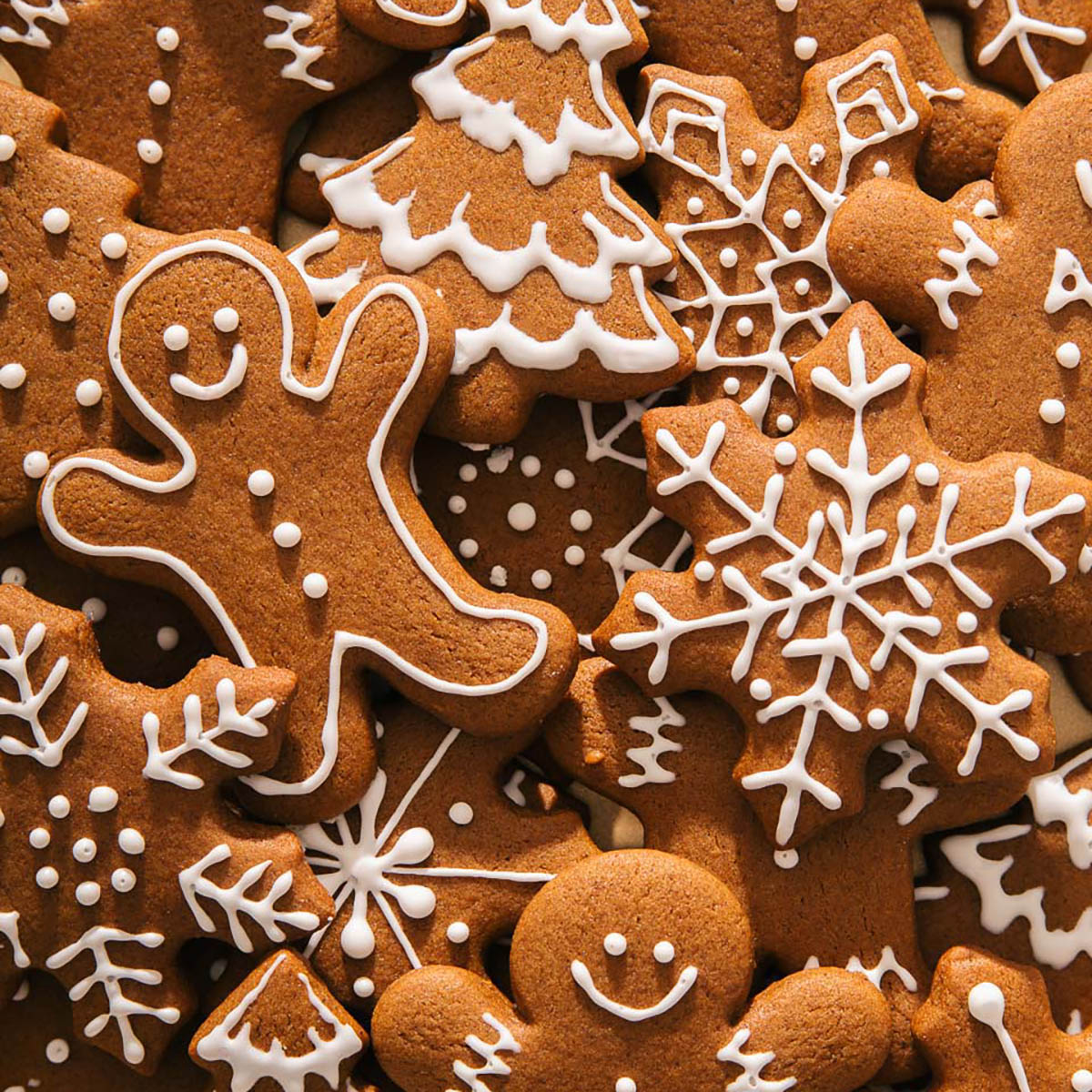 Collection of decorated gingerbread cookies with white icing in festive shapes including snowflakes and gingerbread men