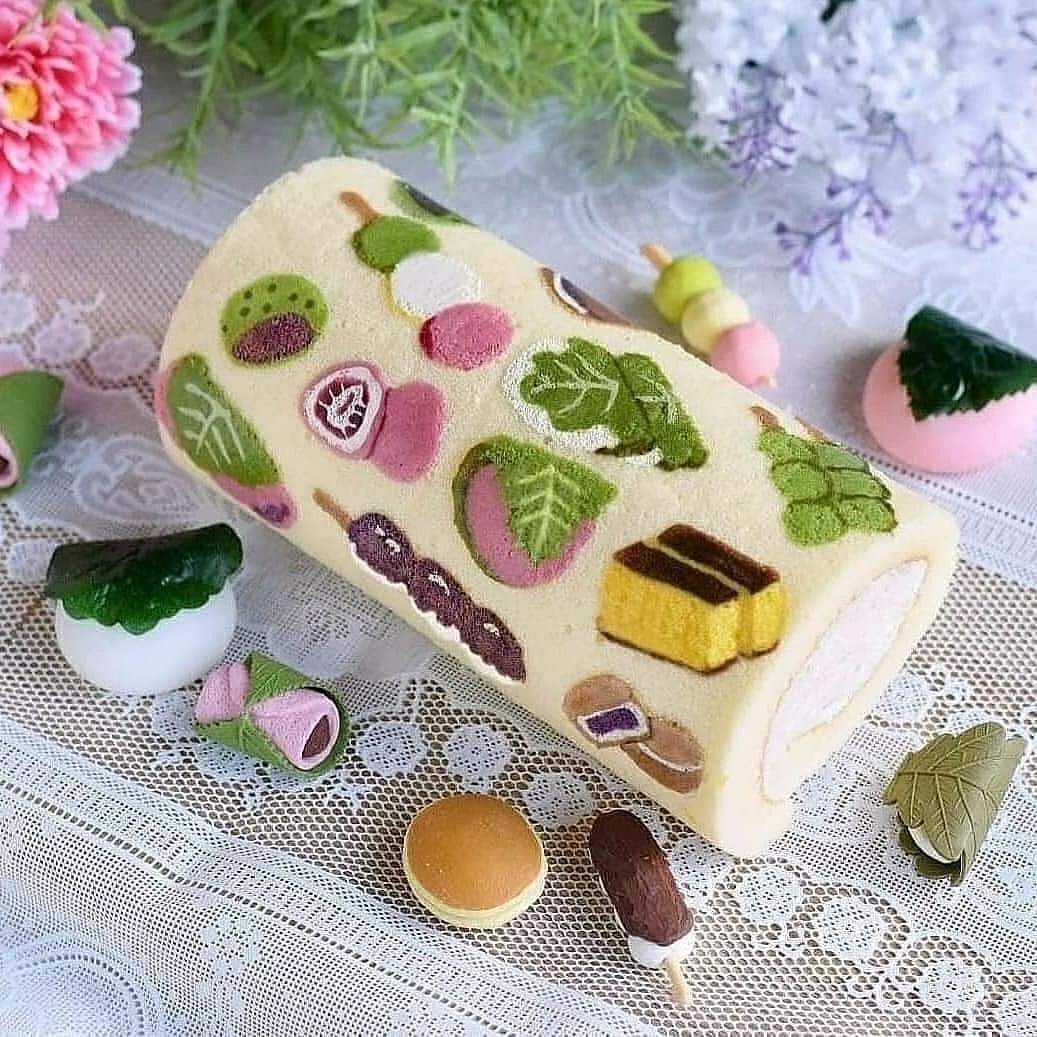 Decorated Swiss roll cake with colorful fruit and leaf patterns on a lace tablecloth