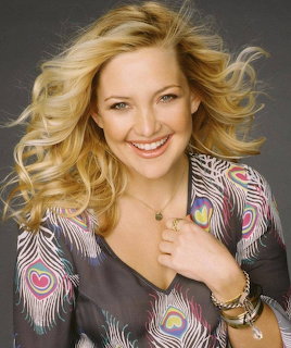 Studio portrait of a smiling blonde woman with wavy hair and a patterned blouse