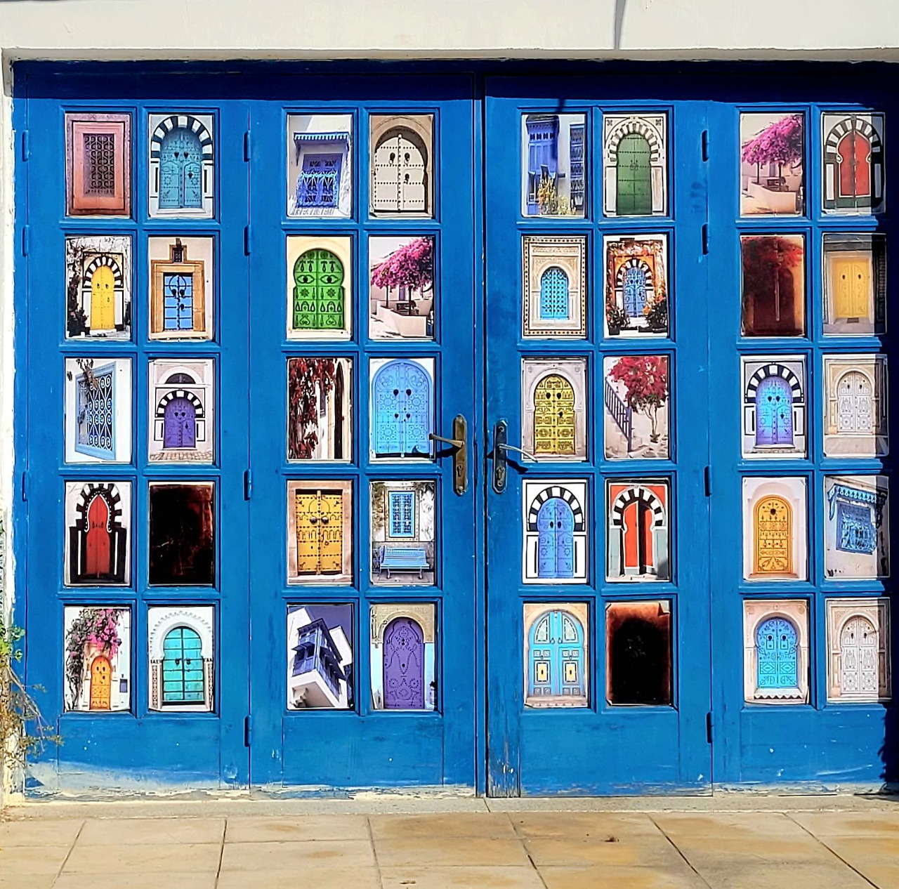 Blue double doors adorned with grid of colorful miniature door photos in Porto