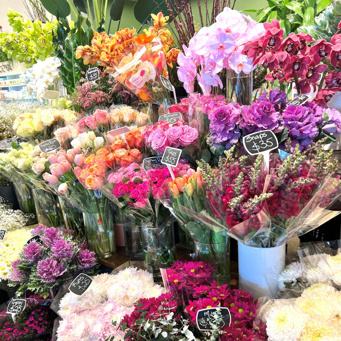 Colorful assortment of fresh flower bouquets displayed at a flower shop including roses, orchids, and carnations