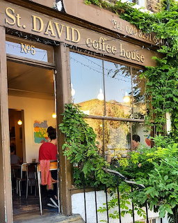 Coffee house exterior overgrown with green vines and climbing plants