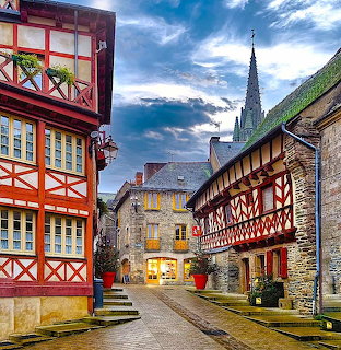 Historic street in Josselin, France with half-timbered houses and a church spire