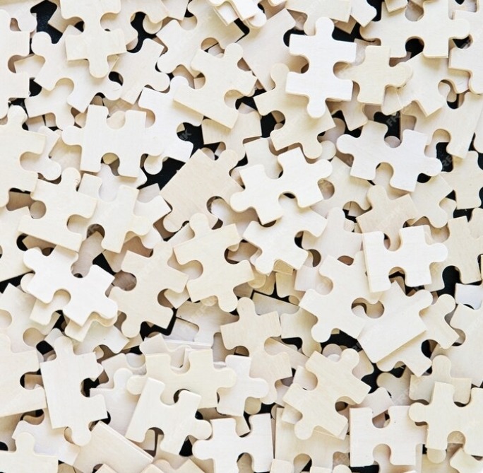 Close-up of scattered blank white jigsaw puzzle pieces