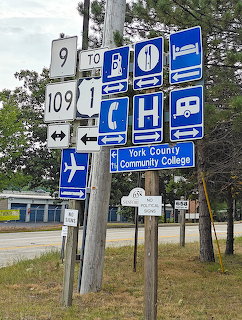Blue and white directional signs on poles showing community services and directions