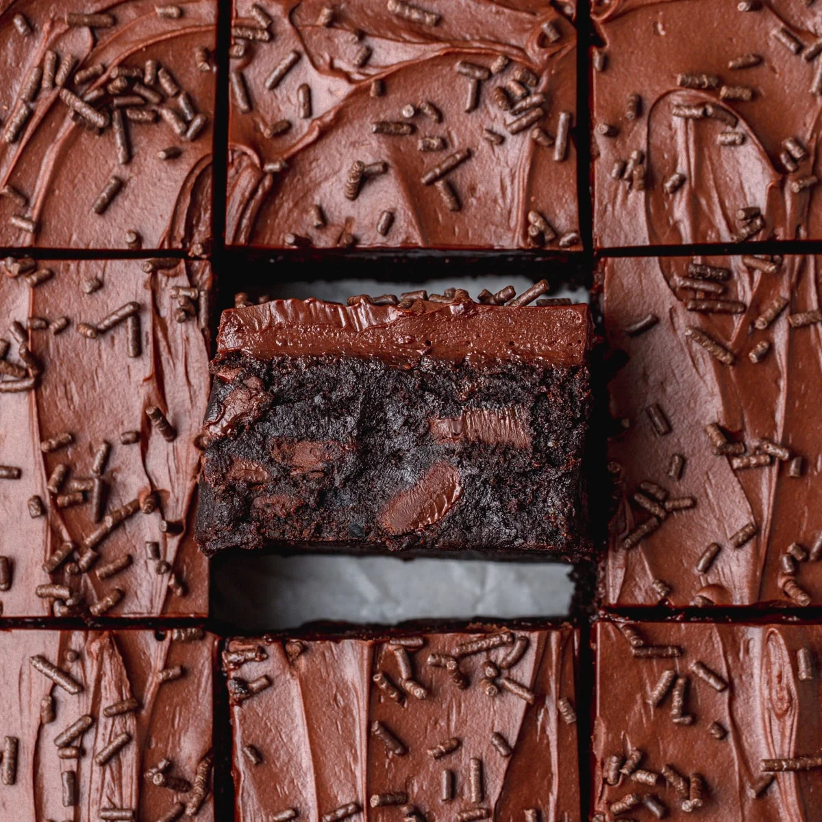 Close-up of frosted chocolate brownies cut into squares with one brownie piece in the center