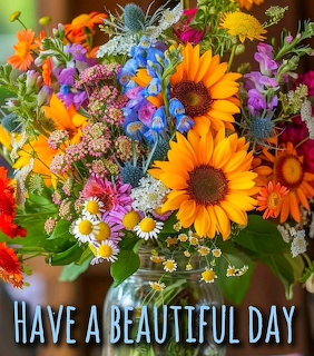 Colorful bouquet with sunflowers, daisies, blue thistle, and wildflowers in a glass vase