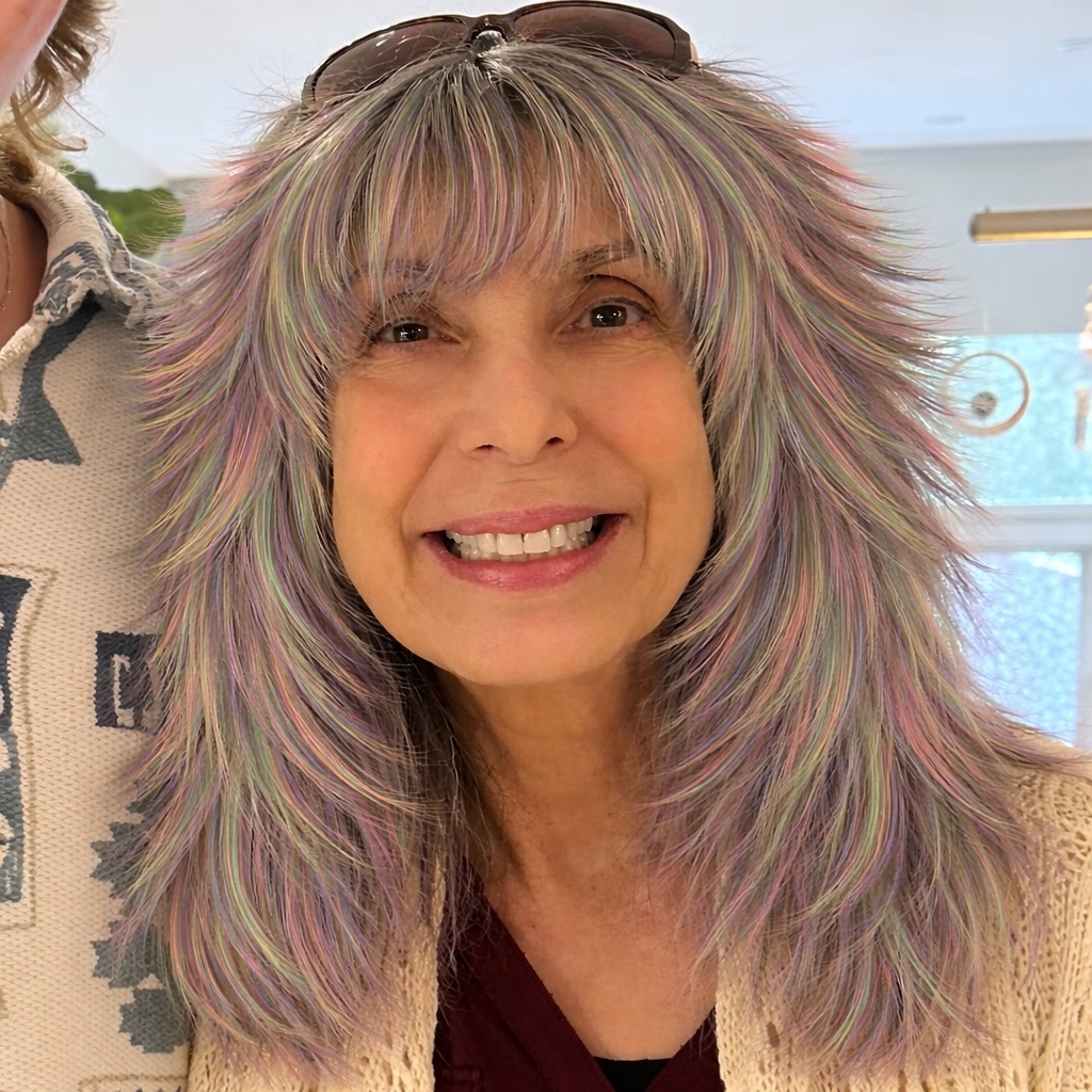 Smiling woman with layered pastel purple and pink hair in an indoor portrait