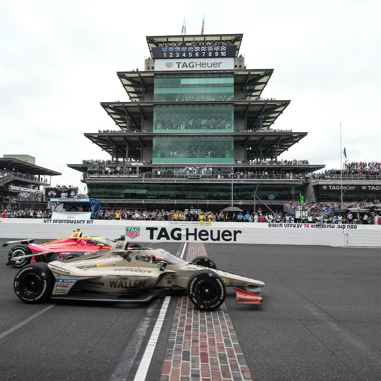 IndyCar crossing the finish line at Indianapolis Motor Speedway with the pagoda behind