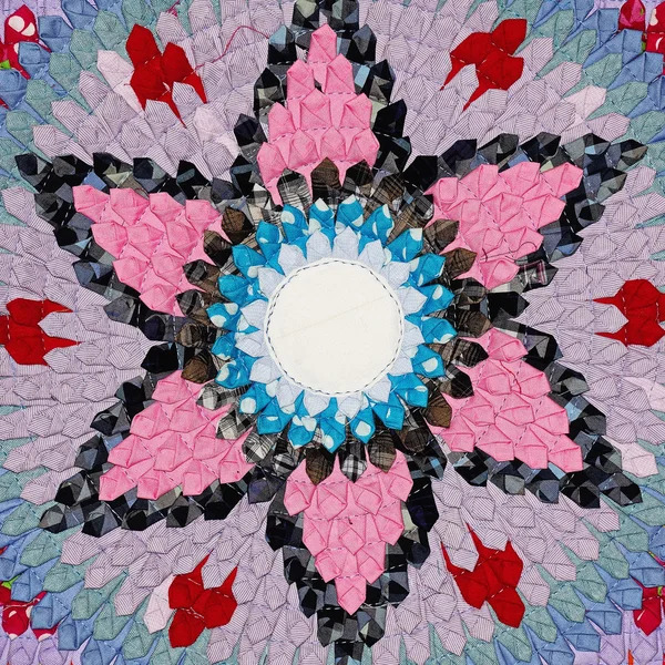 Colorful mandala with pink petals, blue center, and red accents on purple textured background