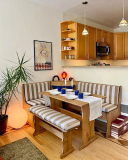 Cozy dining nook with striped bench, wooden table, kitchen cabinets, and pendant lights