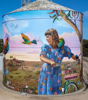 Street art mural on water tank showing woman with parrots and outback landscape in Bute, Australia