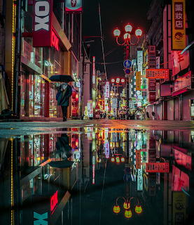 Neon-lit Tokyo street at night reflected in wet pavement with colorful signs and a solitary figure