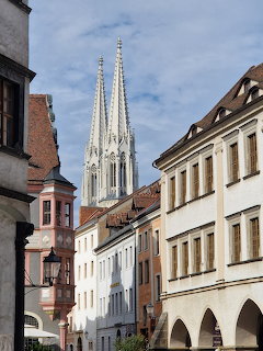 Twin Gothic church spires towering over historic European buildings on a narrow street in Görlitz, Germany