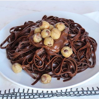 Chocolate pasta noodles with cookie dough balls and chocolate sauce on white plate