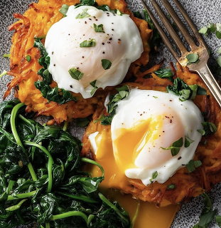 Two poached eggs on sweet potato hash browns with sautéed spinach and fresh herb garnish