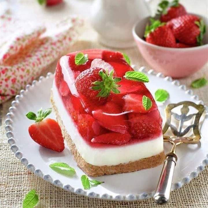 Rectangular strawberry cheesecake with fresh strawberries and mint on white plate