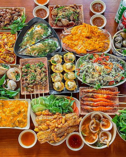 Colorful assortment of Asian street food dishes with skewers, spring rolls, and dipping sauces on wooden table