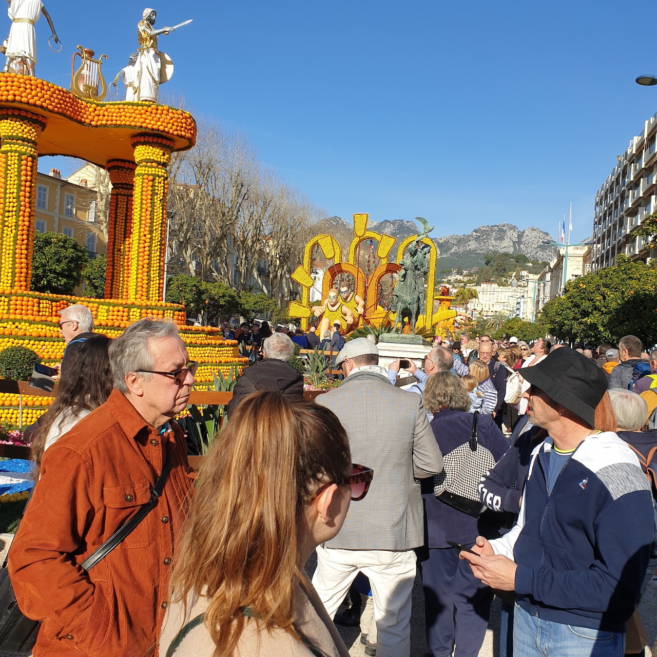 Elaborate citrus-decorated parade float with sculptures at outdoor lemon festival with spectators