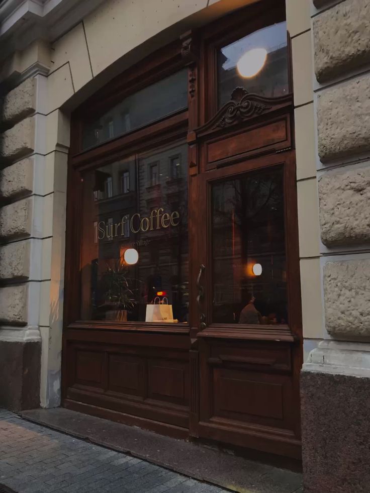 Traditional coffee shop storefront with dark wood facade and illuminated windows at twilight