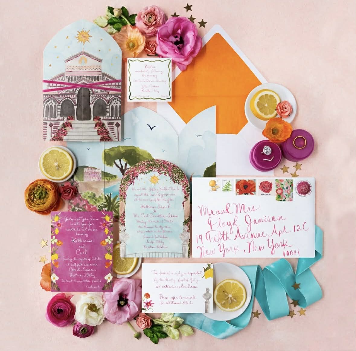 Flat lay of colorful letters, envelopes, cards, flowers, and citrus slices on pink surface