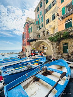 Blue wooden boats on a stone ramp in front of colorful buildings in Cinque Terre, Italy