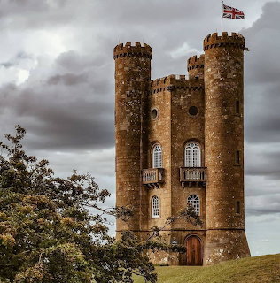 Broadway Tower on a grassy hill beneath dark cloudy skies