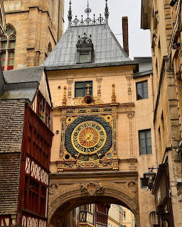 Historic ornate clock above an archway between old buildings in a narrow city street