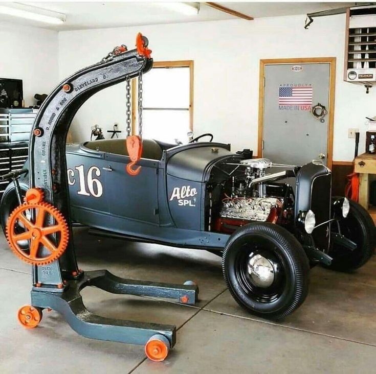 Vintage black hot rod in a garage next to an engine hoist