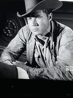Black and white portrait of person in cowboy hat and Western clothing