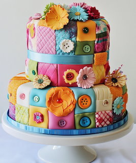 Three-tier cake with colorful patchwork fondant decoration featuring buttons, flowers, and quilt patterns
