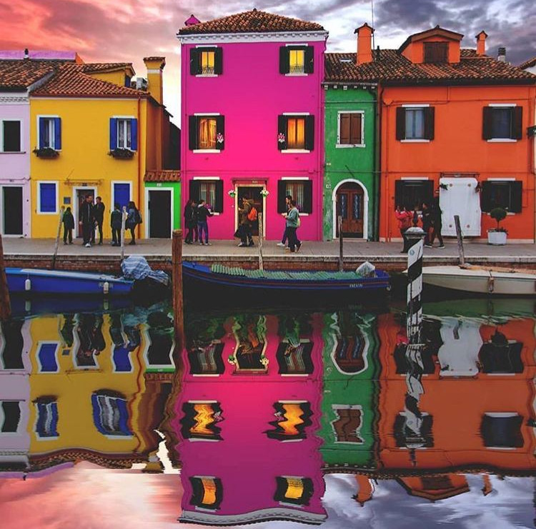 Colorful canal houses at sunset with bright reflections in calm water