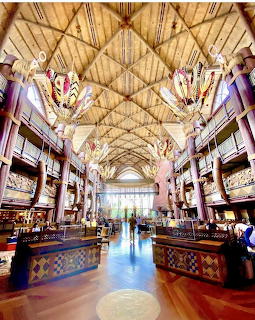 Symmetrical hotel lobby with wooden vaulted ceiling and colorful hanging chandeliers