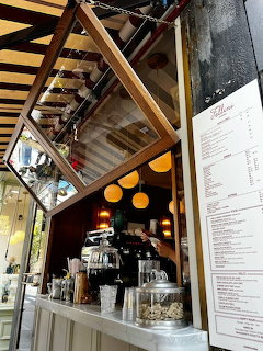 Overhead view of cafe counter with espresso machine, yellow decor, mirrors, and menu on wall