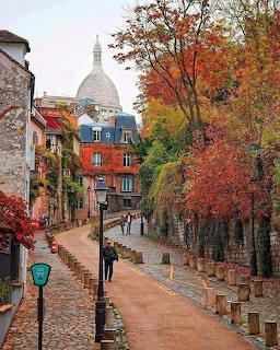 Autumn street scene in Montmartre, Paris with colorful trees and Sacré-Cœur basilica dome in background
